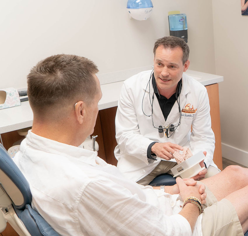 Dr. Dana Shumate with a male patient deep in conversation inside his clinic at Porters Neck Dentistry in Wilmington NC
